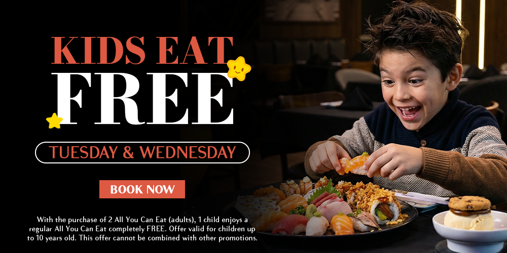A happy young boy eating sushi at a restaurant table.